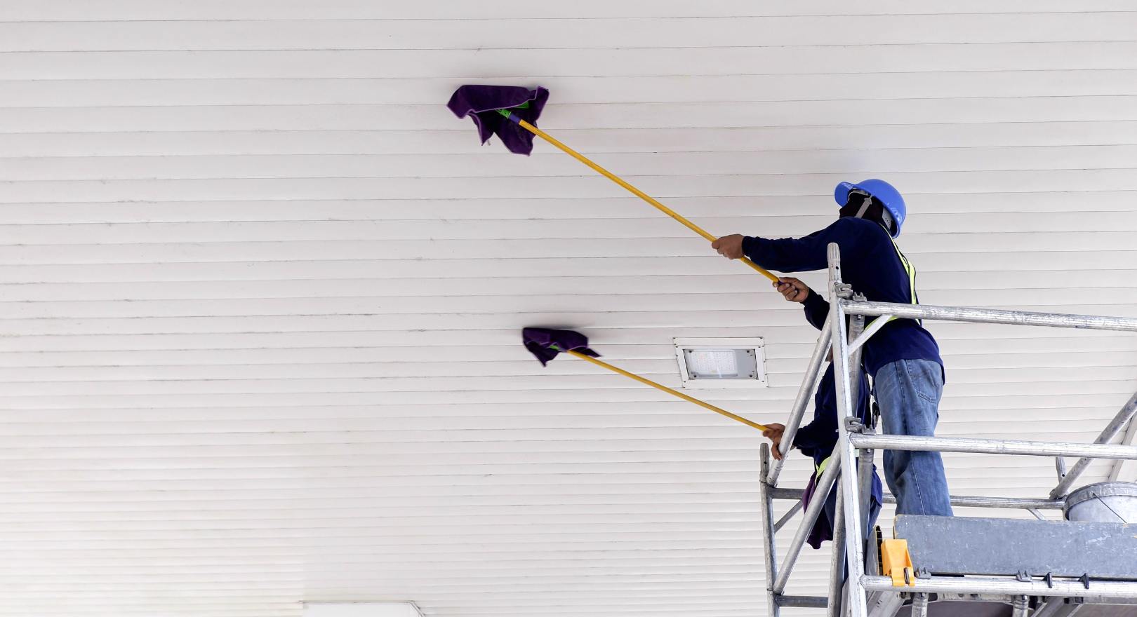 pracownicy na rusztowaniach myją brudny sufit