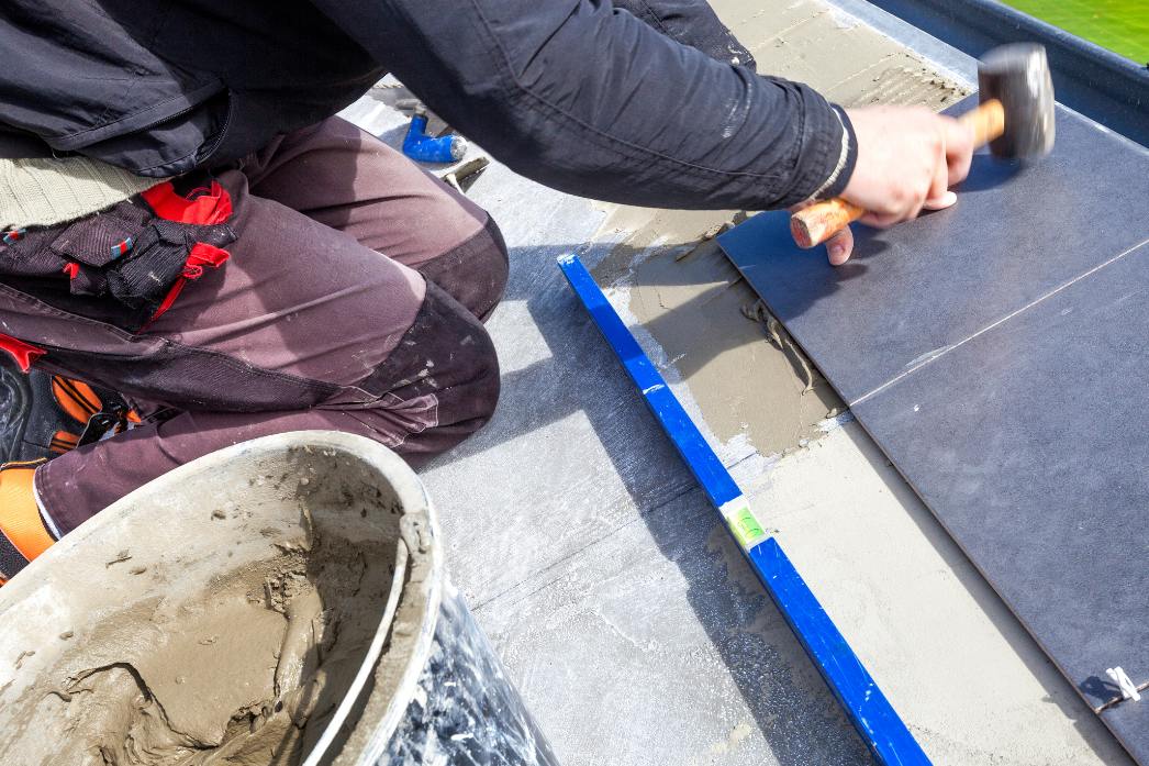 mężczyzna przykleja płytki na tarasie